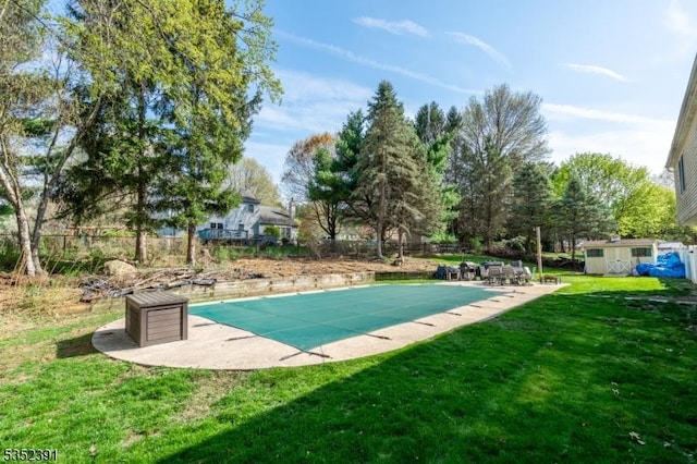 view of swimming pool featuring an outdoor structure, a patio, a yard, and a covered pool