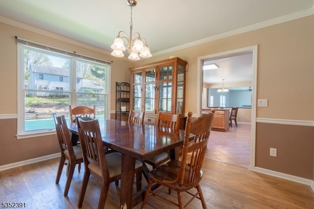 dining room featuring ornamental molding, light wood finished floors, an inviting chandelier, and baseboards