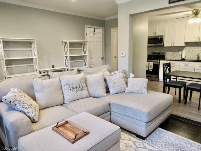 living room with ceiling fan, light wood-style flooring, and ornamental molding