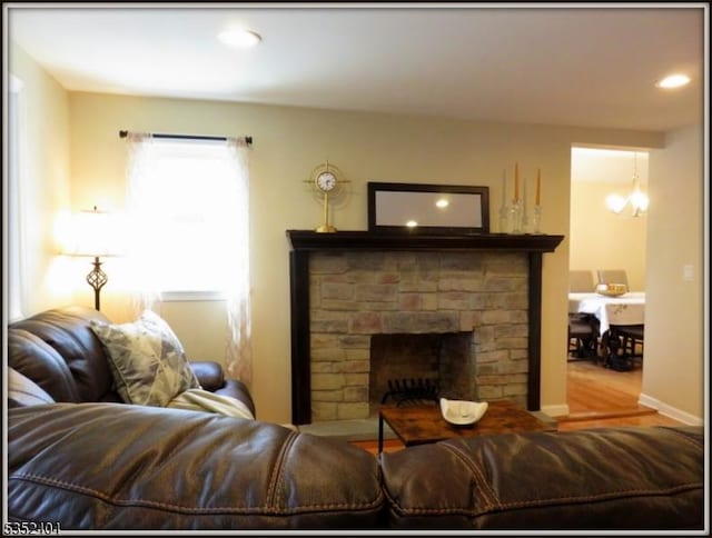 living area with a brick fireplace, recessed lighting, an inviting chandelier, and wood finished floors
