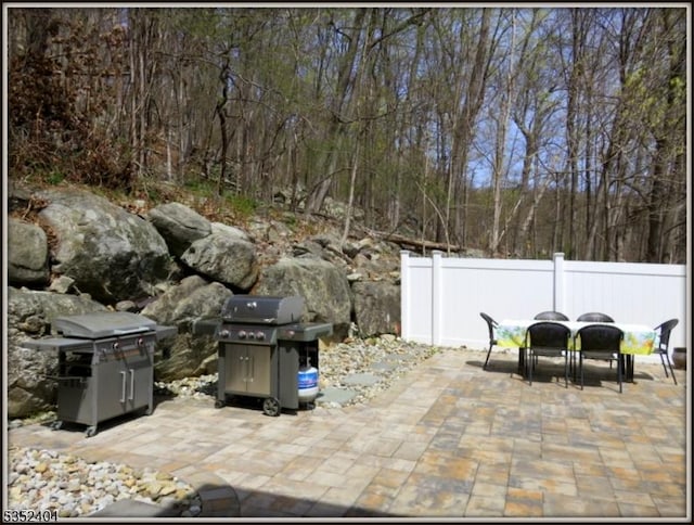 view of patio featuring area for grilling, fence, and outdoor dining space