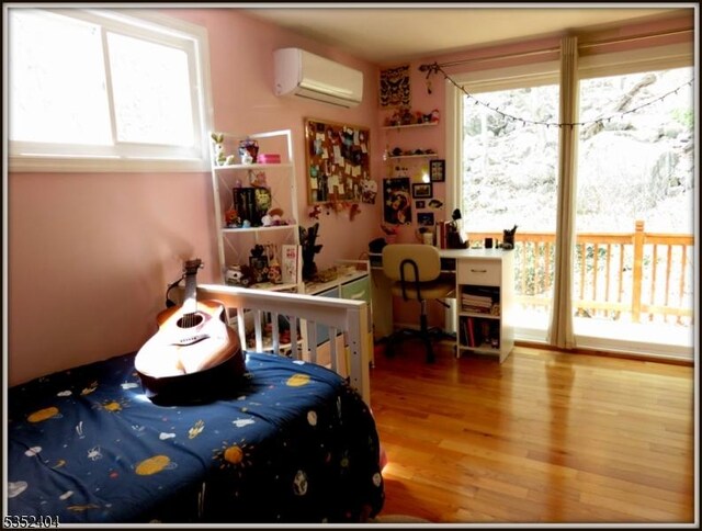 bedroom with wood finished floors and a wall mounted AC