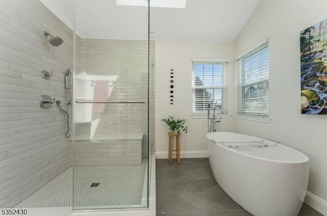 full bath featuring a freestanding bath, baseboards, tile patterned flooring, and tiled shower