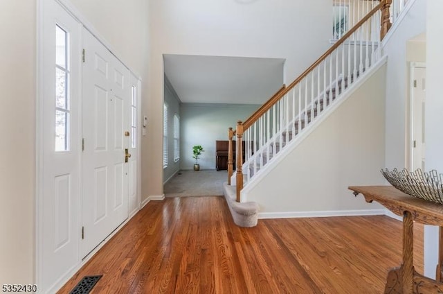 entrance foyer featuring stairway, baseboards, wood finished floors, and visible vents