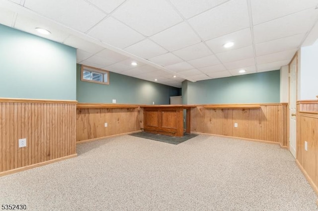 finished below grade area featuring wainscoting, a dry bar, a paneled ceiling, and carpet floors