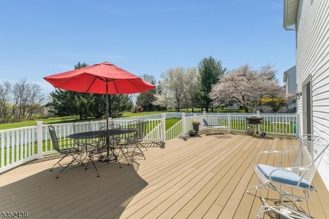 deck with outdoor dining area, a grill, and a yard