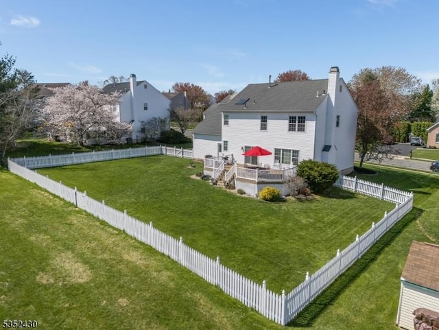 rear view of property featuring a lawn, a chimney, and a fenced backyard