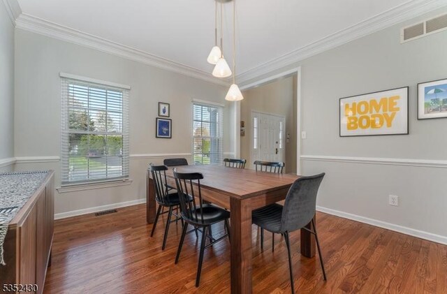 dining space featuring dark wood finished floors, baseboards, crown molding, and visible vents