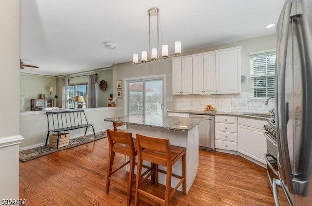 kitchen featuring a kitchen island, white cabinetry, stainless steel appliances, and a sink