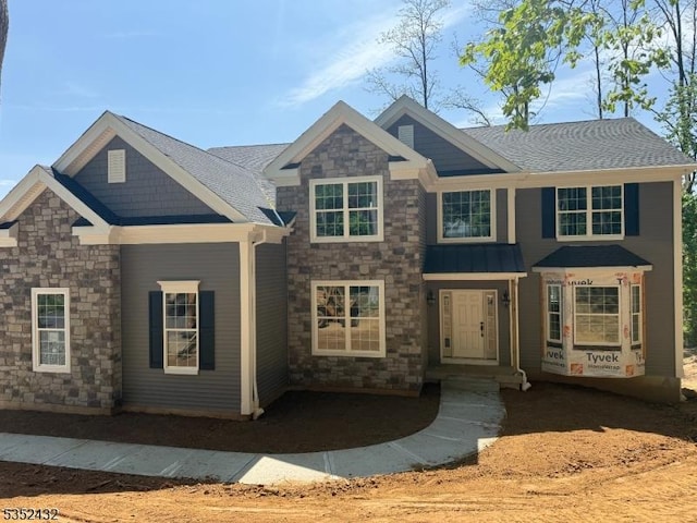 craftsman-style home with a shingled roof and stone siding
