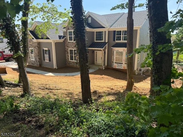 exterior space featuring roof with shingles and stone siding