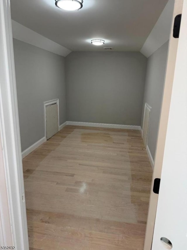 empty room with baseboards, light wood-style flooring, and lofted ceiling