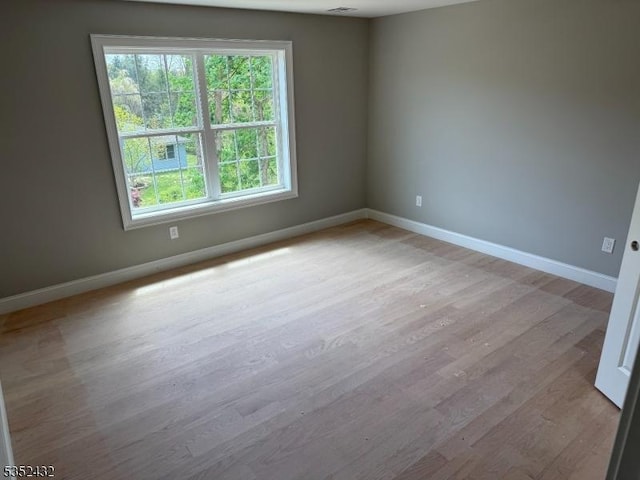 empty room with baseboards, a wealth of natural light, and wood finished floors