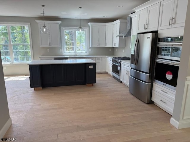kitchen featuring light wood-style floors, light countertops, wall chimney exhaust hood, and stainless steel appliances