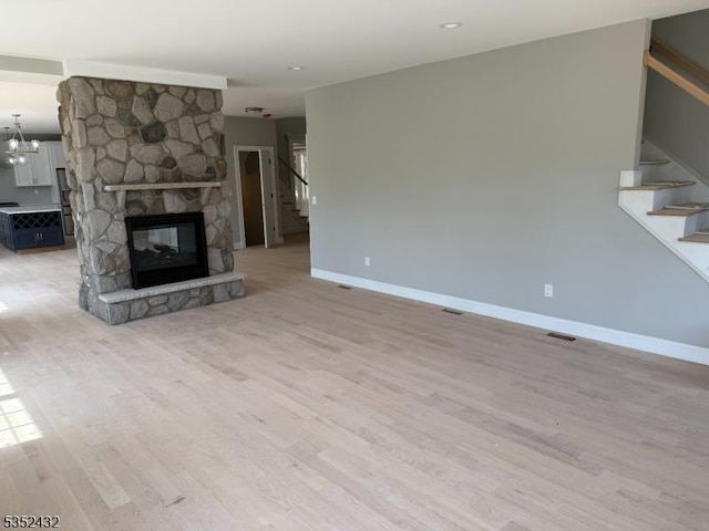 unfurnished living room with stairs, baseboards, and light wood finished floors
