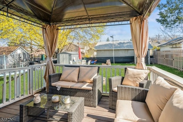 wooden terrace featuring a gazebo, fence, an outbuilding, an outdoor hangout area, and a shed