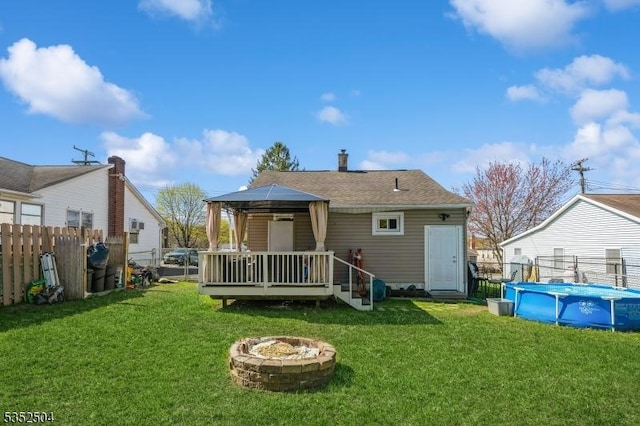 rear view of property with fence, a fire pit, a gazebo, and a deck