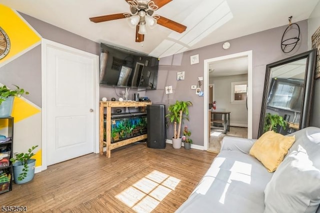 living area featuring wood finished floors, a ceiling fan, vaulted ceiling, and baseboards