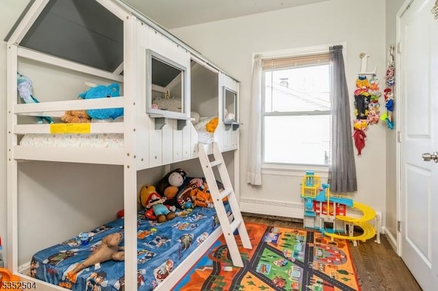 bedroom with wood finished floors and a baseboard heating unit