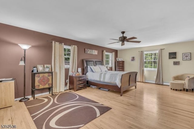 bedroom with baseboards, a baseboard radiator, light wood-style flooring, and ceiling fan
