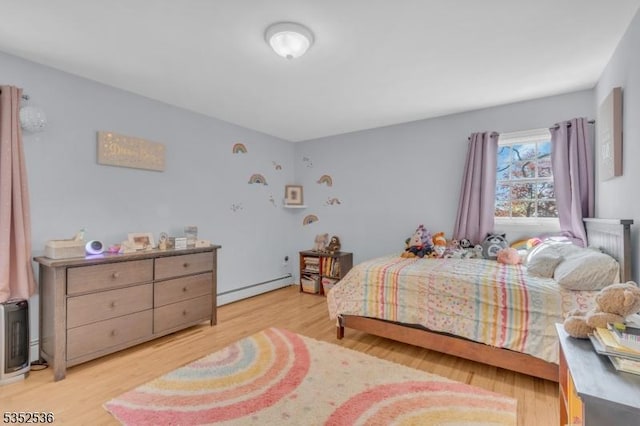 bedroom with a baseboard heating unit and light wood finished floors