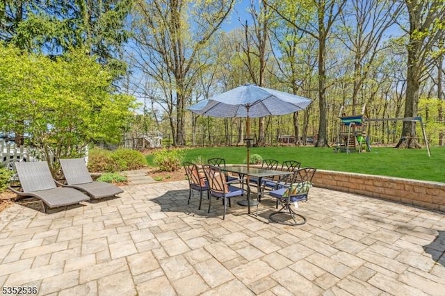 view of patio / terrace featuring fence, outdoor dining area, and a playground