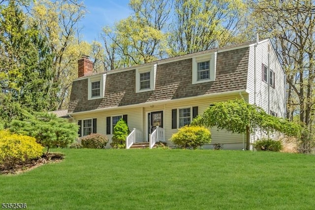 colonial inspired home featuring a front yard, a chimney, and roof with shingles