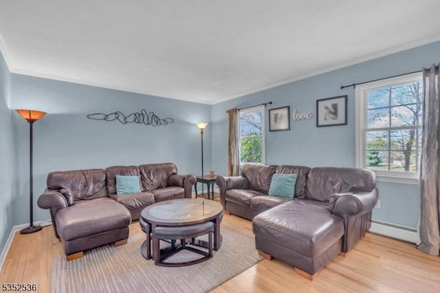 living room with crown molding, baseboards, baseboard heating, and light wood-style flooring
