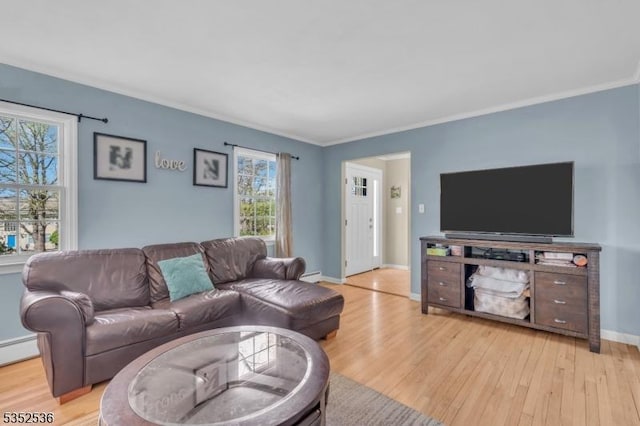 living room featuring plenty of natural light, light wood-style flooring, and crown molding