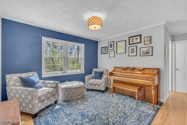 sitting room with baseboards, ornamental molding, and wood finished floors