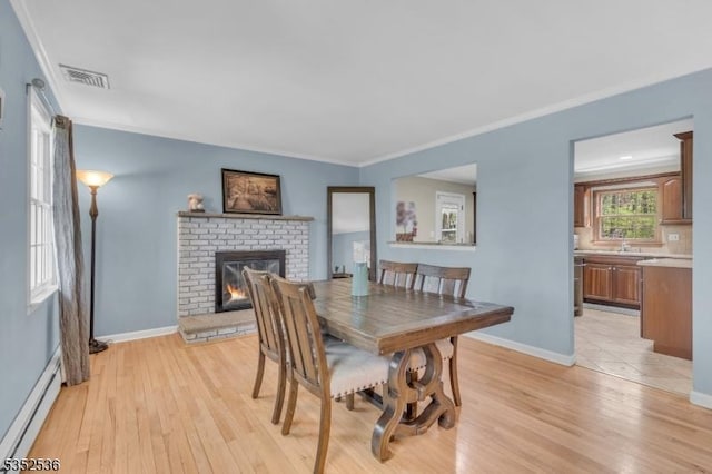 dining room featuring visible vents, a baseboard radiator, light wood finished floors, and crown molding
