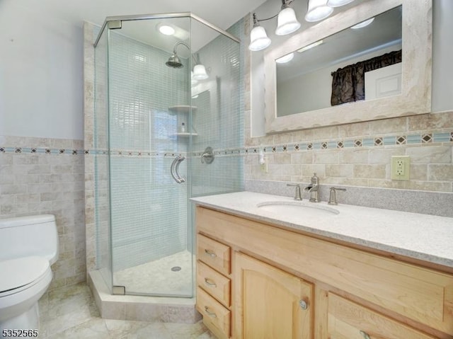 full bathroom featuring toilet, tile walls, a shower stall, and vanity