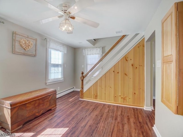interior space featuring baseboard heating, baseboards, wood finished floors, and a ceiling fan