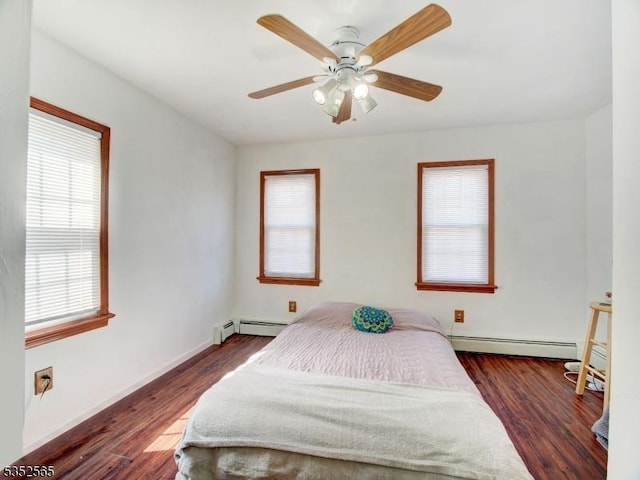 bedroom with wood finished floors, baseboard heating, and multiple windows