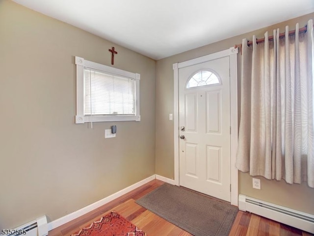 foyer entrance with baseboards, wood finished floors, and a baseboard radiator
