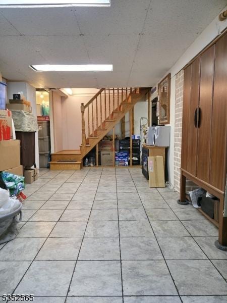 finished below grade area featuring stairs and light tile patterned flooring