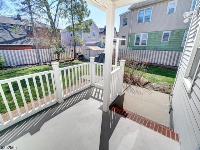 view of patio with fence, a storage shed, a residential view, and an outbuilding