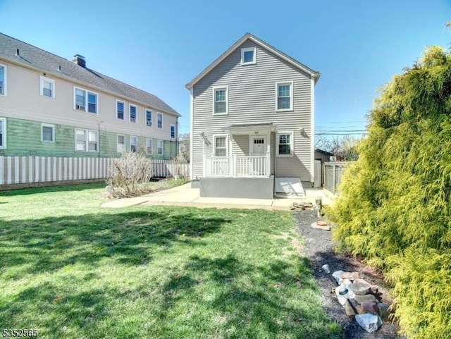 rear view of property featuring a yard, a patio area, and fence
