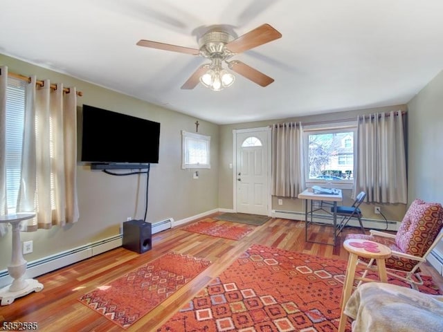 living room featuring a baseboard radiator, wood finished floors, ceiling fan, and baseboards