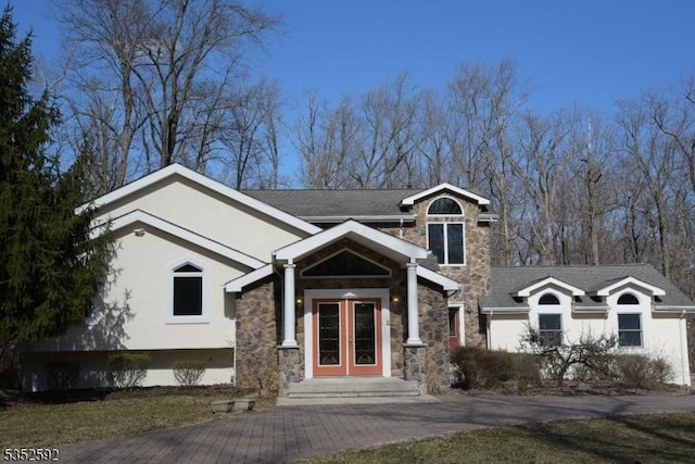 view of front facade featuring french doors, stucco siding, and stone siding