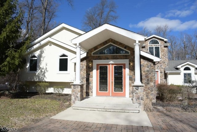 view of front of house with french doors, stucco siding, and stone siding