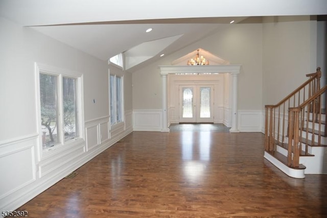 foyer entrance with a decorative wall, vaulted ceiling, wood finished floors, and a notable chandelier