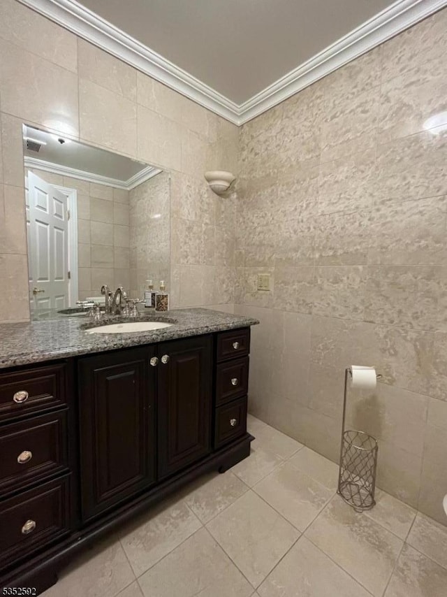 bathroom with tile walls, tile patterned flooring, ornamental molding, and vanity