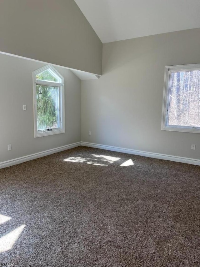 interior space with baseboards, lofted ceiling, and dark colored carpet