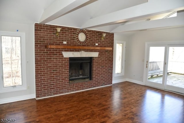 unfurnished living room with baseboards, a wealth of natural light, beam ceiling, and wood finished floors