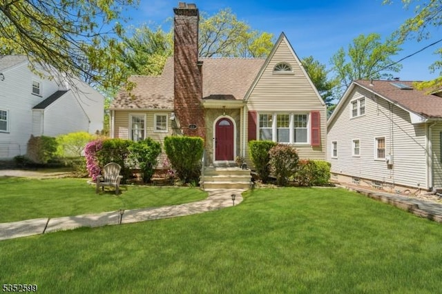 tudor-style house featuring a chimney and a front yard