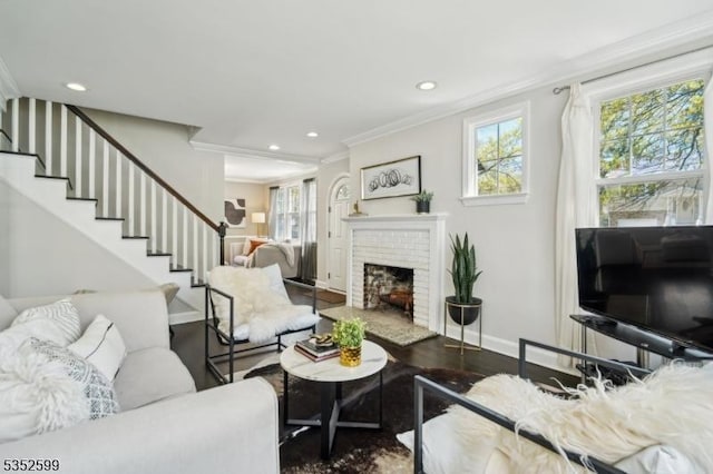 living area featuring crown molding, a fireplace, baseboards, stairway, and recessed lighting