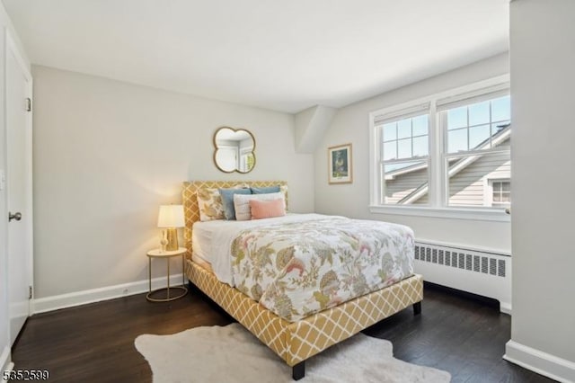 bedroom featuring baseboards, radiator heating unit, and wood finished floors