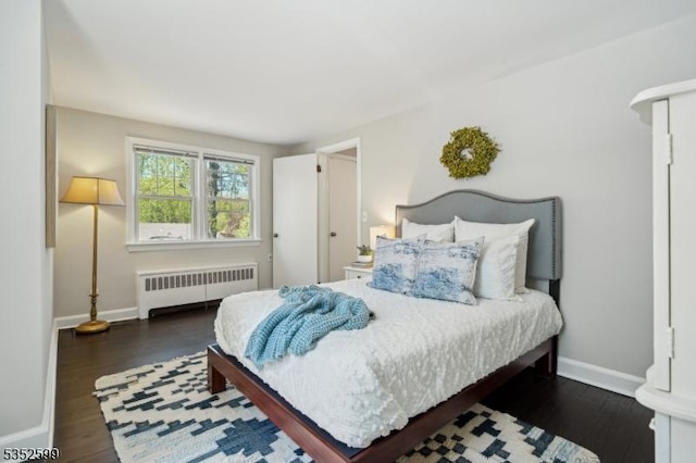 bedroom with radiator heating unit, baseboards, and wood finished floors