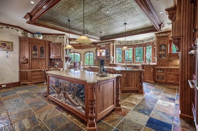 770 Pottersville Rd, Chester Twp, NJ 07931 - kitchen with ornamental molding, a center island with sink, stone tile floors, brown cabinets, and a raised ceiling